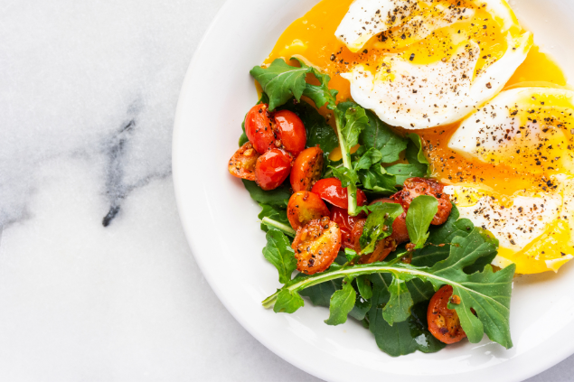 Alimentação saudável. Prato com ovos mexidos e sala de rúcula com tomate. 