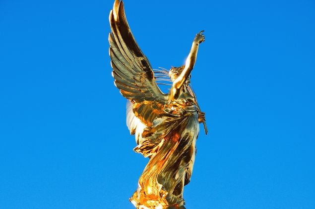 Imagem da estátua de um anjo dourado com uma das mãos erguida ao céu