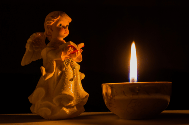 Imagem representativa do anjo da guarda Haziel. A mini estátua de anjo está próxima a uma vela. 