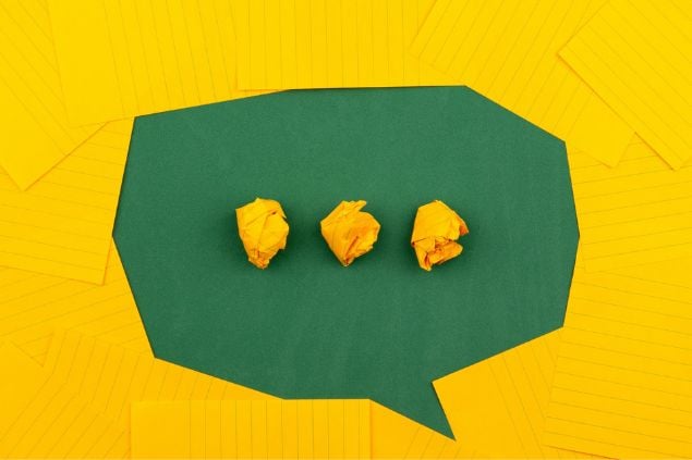 Balão de fala com reticências dentro. Arte feita com pedaços de papéis verdes e amarelos.