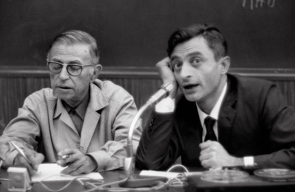 Jean-Paul Sartre escrevendo ao lado de outro homem