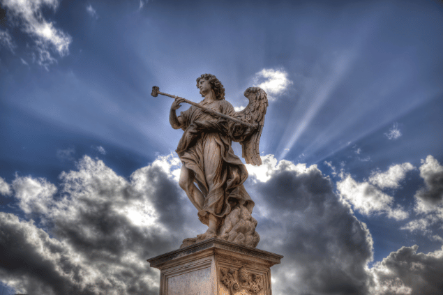 Estátua de anjo representando Achaiah em um céu azul com nuvens. 