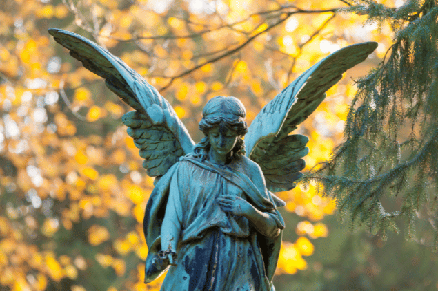 Imagem representativa do anjo da guarda Nanael. A estátua de anjo está em uma floresta com folhas amarelas. 