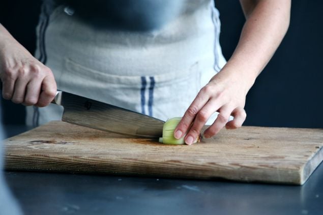 Uma pessoa cortando uma cebola com a faca.