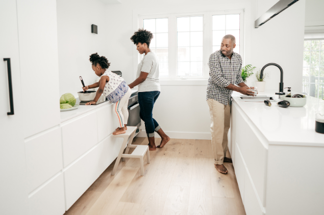 Mulher, homem e criança cozinhando em conjunto em uma cozinha