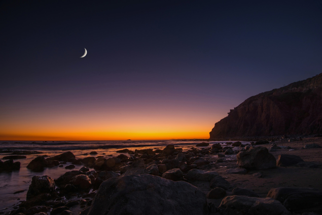 Lua Nova durante pôr do sol em uma praia