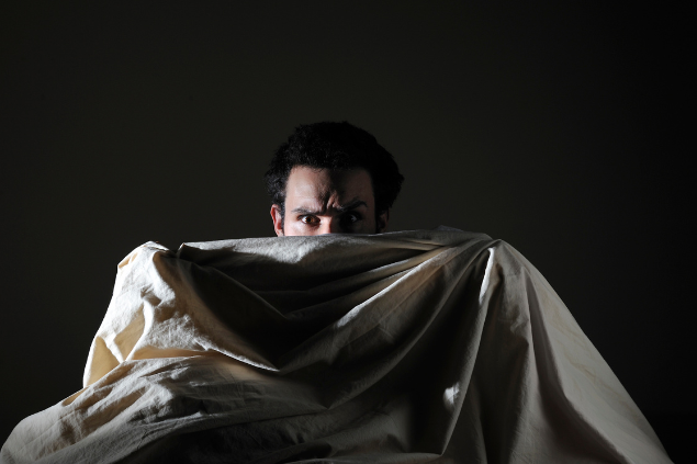 Homem deitado, se escondendo atrás de lençol