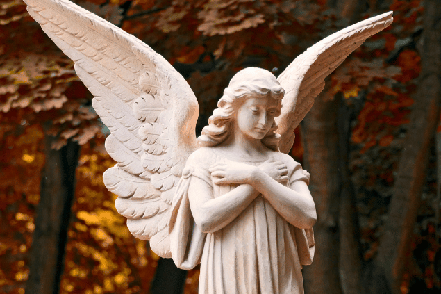 Estátua de anjo com as mãos cruzadas sob o peito