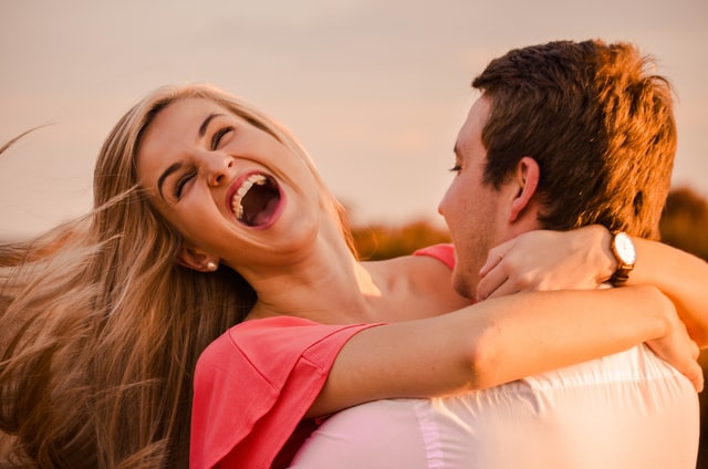Homem e mulher brancos abraçados com expressões sorridentes.