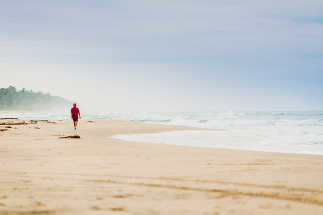 Pessoa andando na beira do mar na praia.