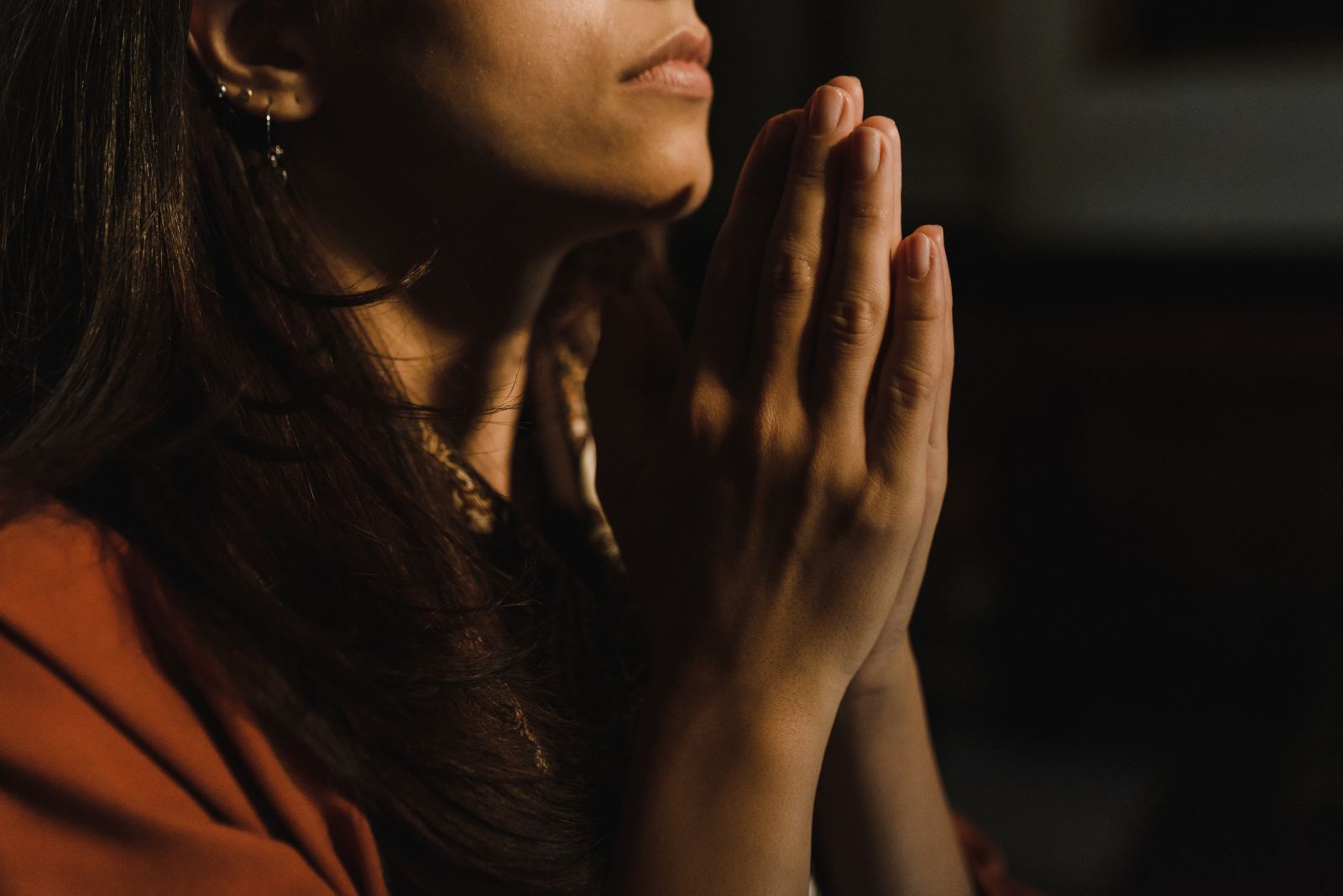 Mulher com as mãos unidas orando 